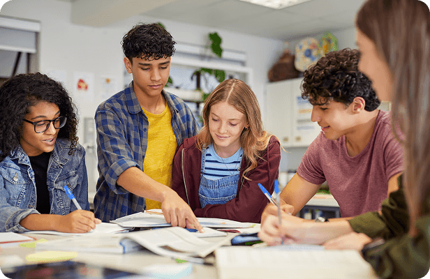 Students pointing at work spread across a table
