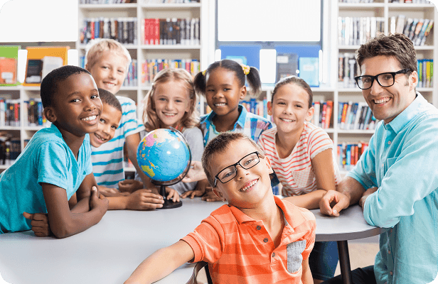 A teacher and young students around a globe in a library