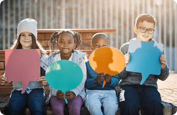 Young students holding up colorful speech bubble signs