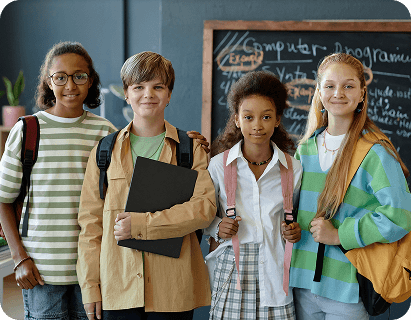 Young students with backpacks in front of a chalkboard